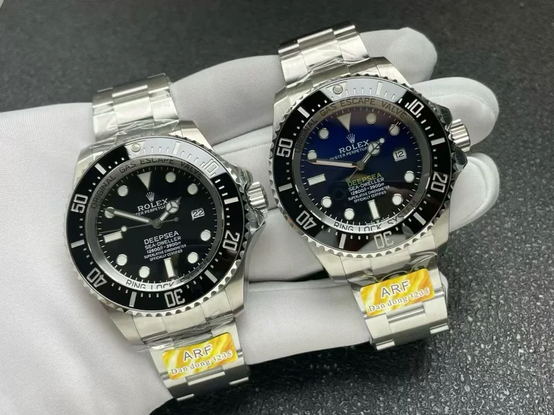 Black and D-Blue dial versions side by side, angled, held in a white glove, factory tag on the bracelets